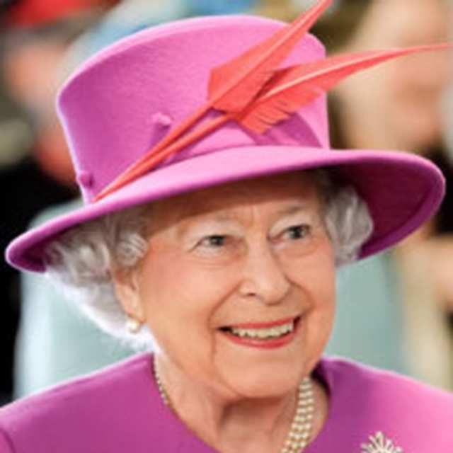 Queen Elizabeth II smiling in a pink coat and hat with orange feathers 