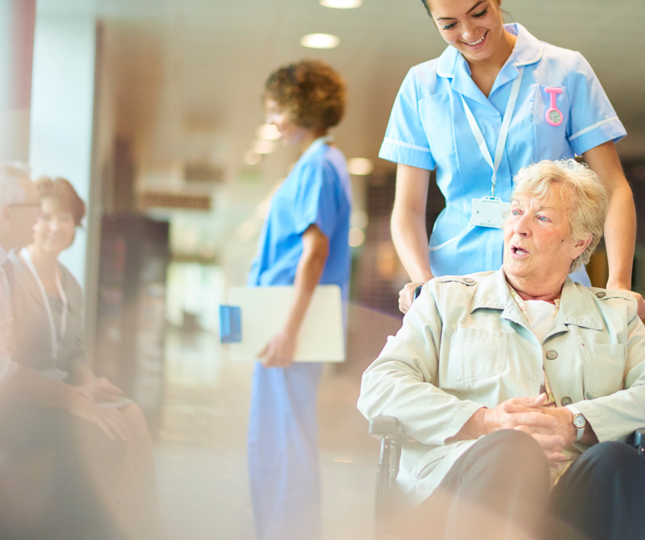 An older woman in a wheelchair talks to a young female healthcare professional 