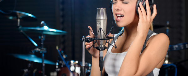 A young women sings into a mic at a recording studio