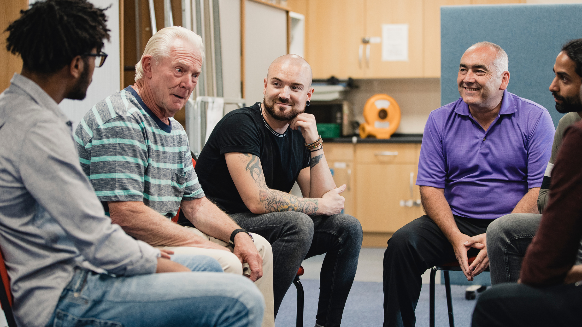 A group of diverse men sit together and talk 