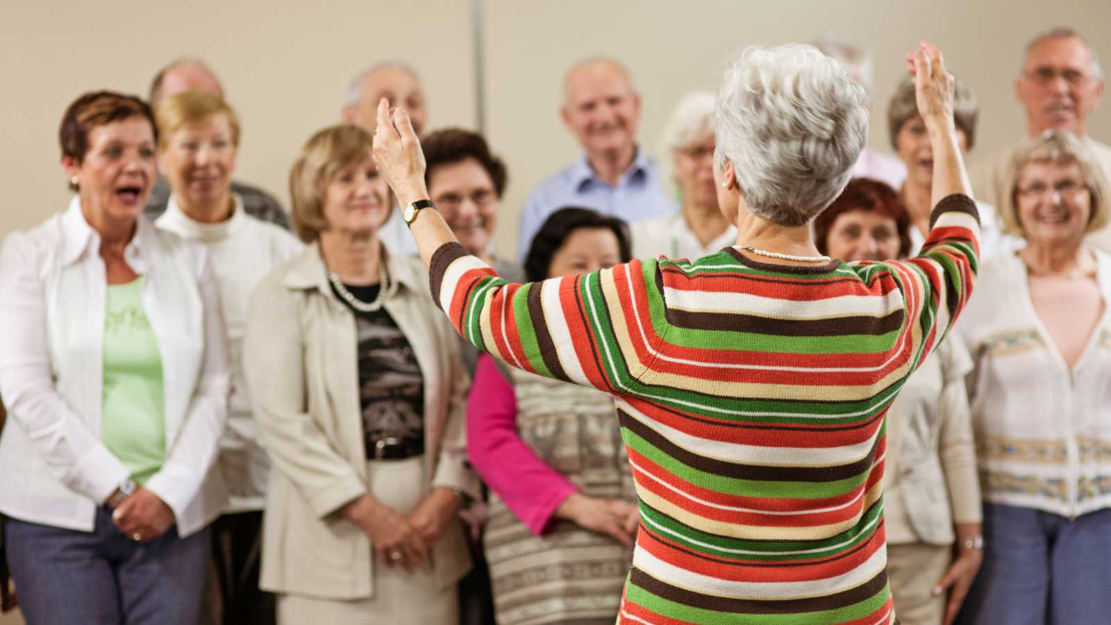 Older woman directing a choir of singers 
