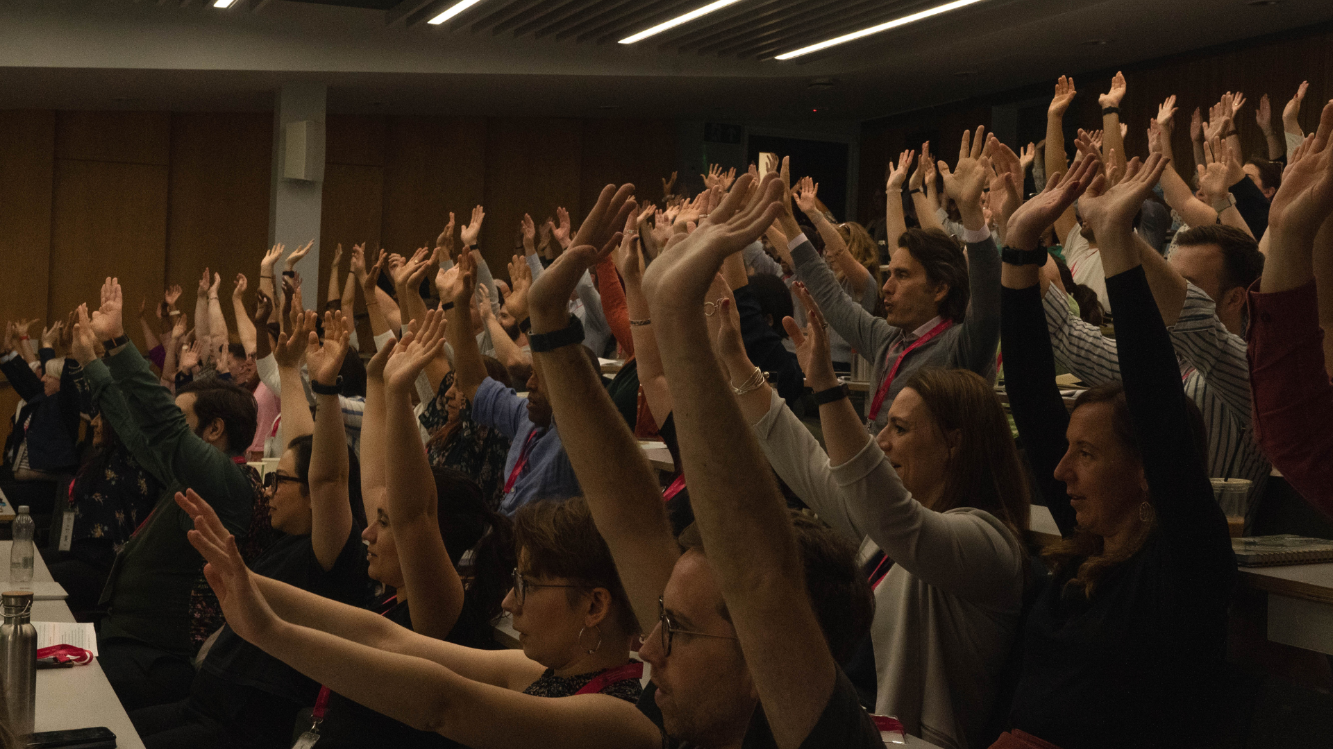 Audience seated all raise both hands in the air 