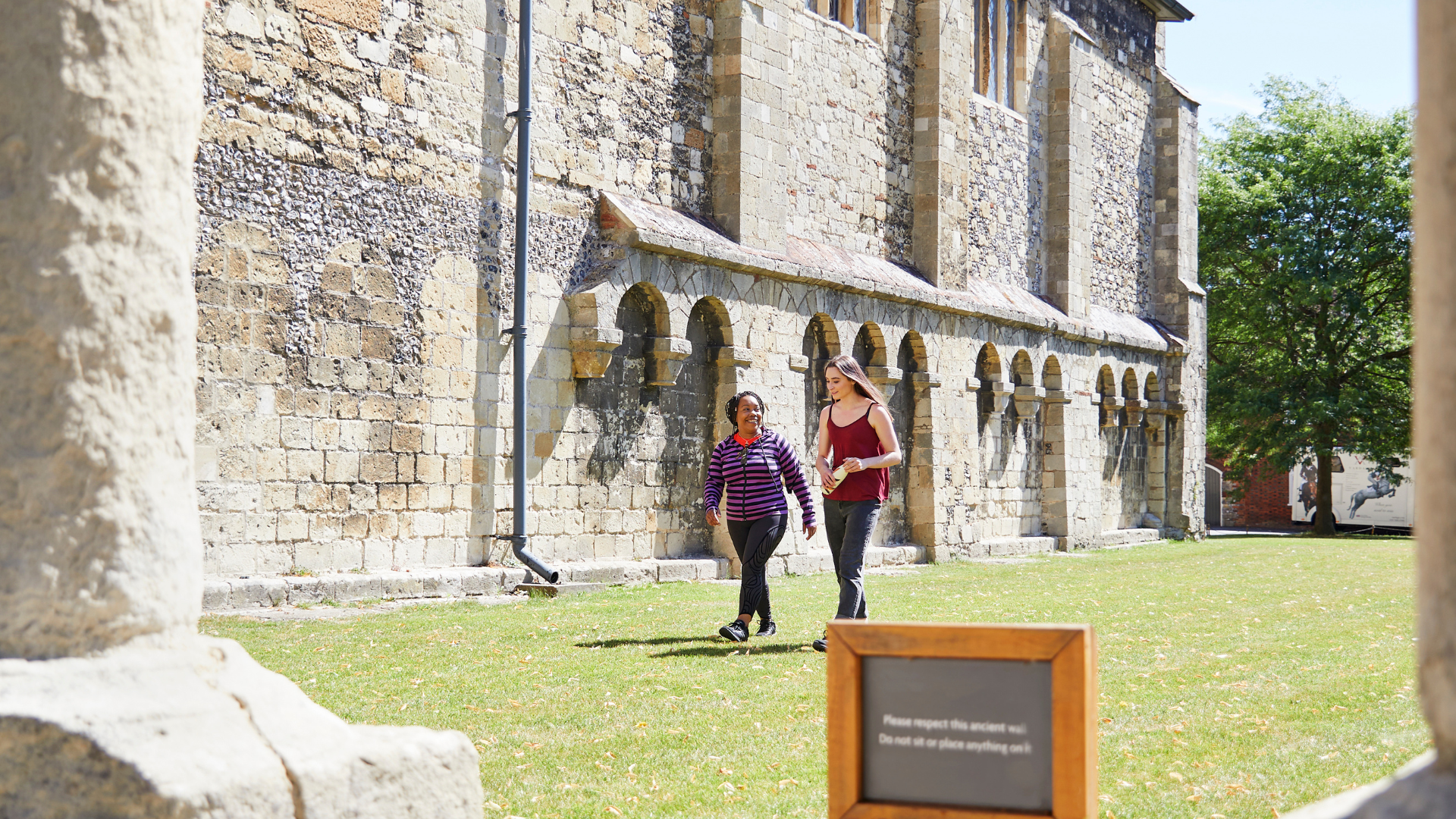 Two women walk together outside an old heritage building 