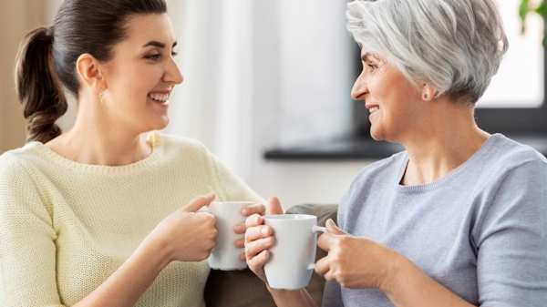 Two women of different ages face each other and chat while having a cup of tea