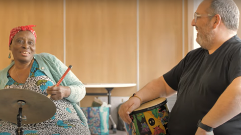 A man and woman play drums together