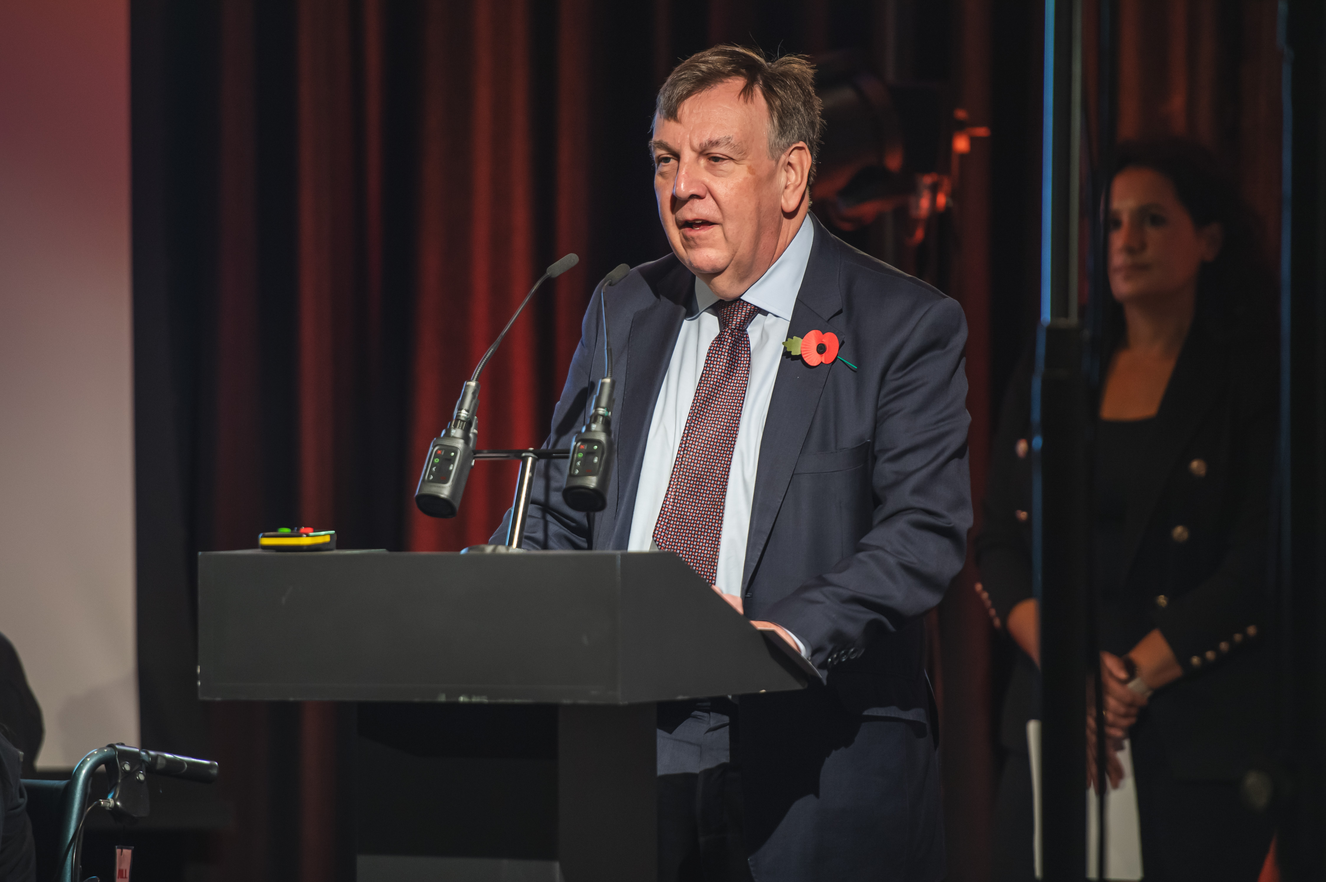 John Whittingdale stands at lectern giving a speech