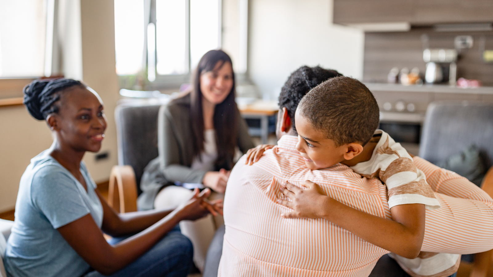A child hugs his father with a mother and family counsellor smiling at them