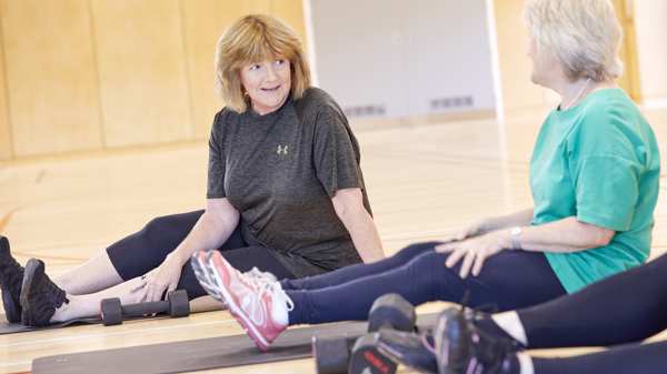 Two woman sit and chat at a gym studio during a class