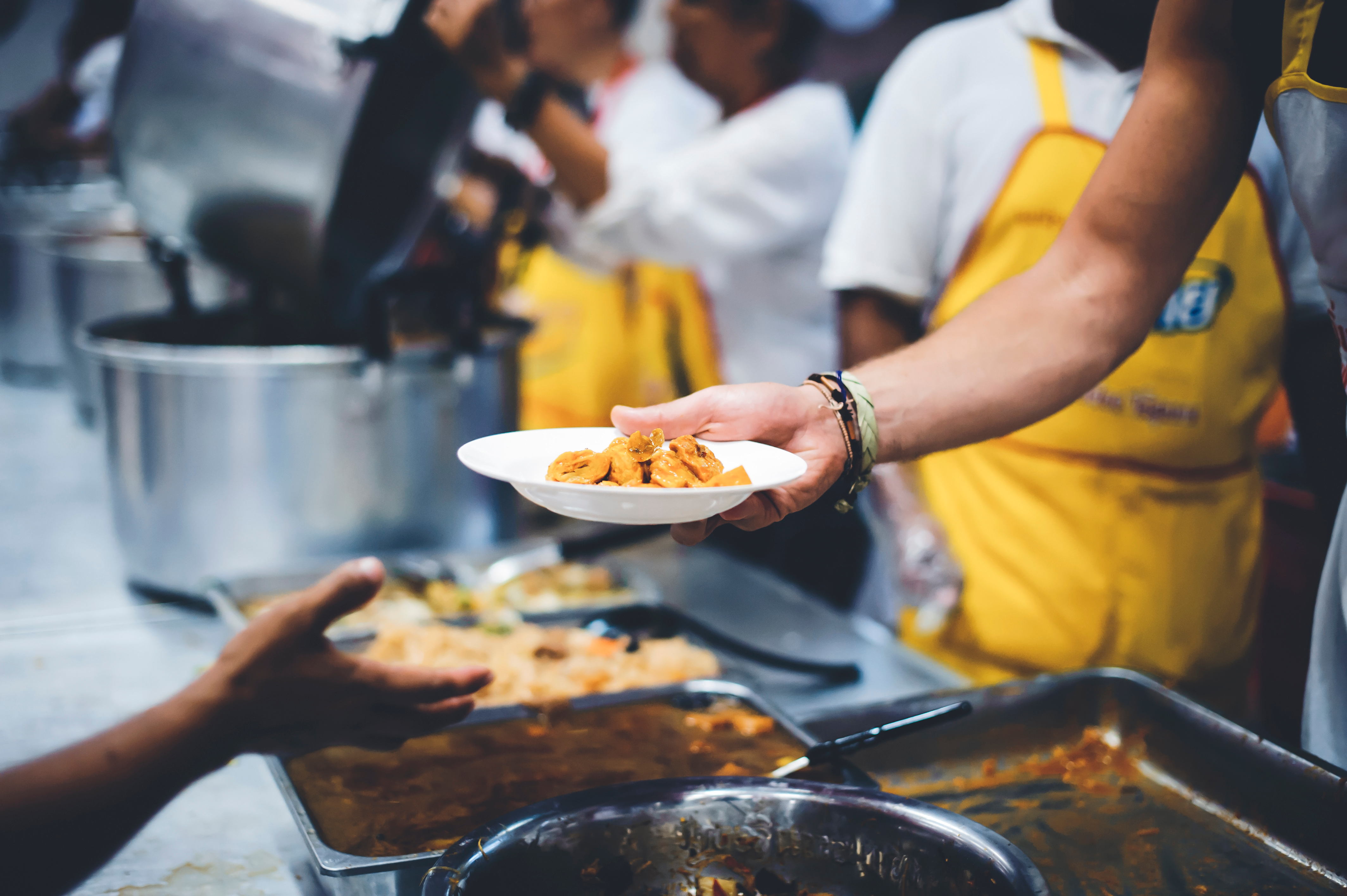 A chef in a community kitchen handing a plate of food to a client