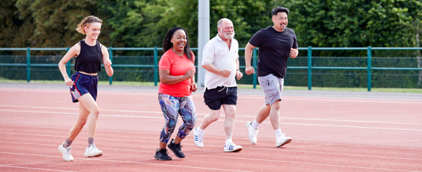 A group if ethnically diverse adults run on an athletics track