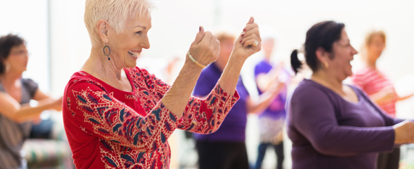 A group of women dance and smile during a movement class
