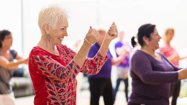 A group of women dance and smile during a movement class