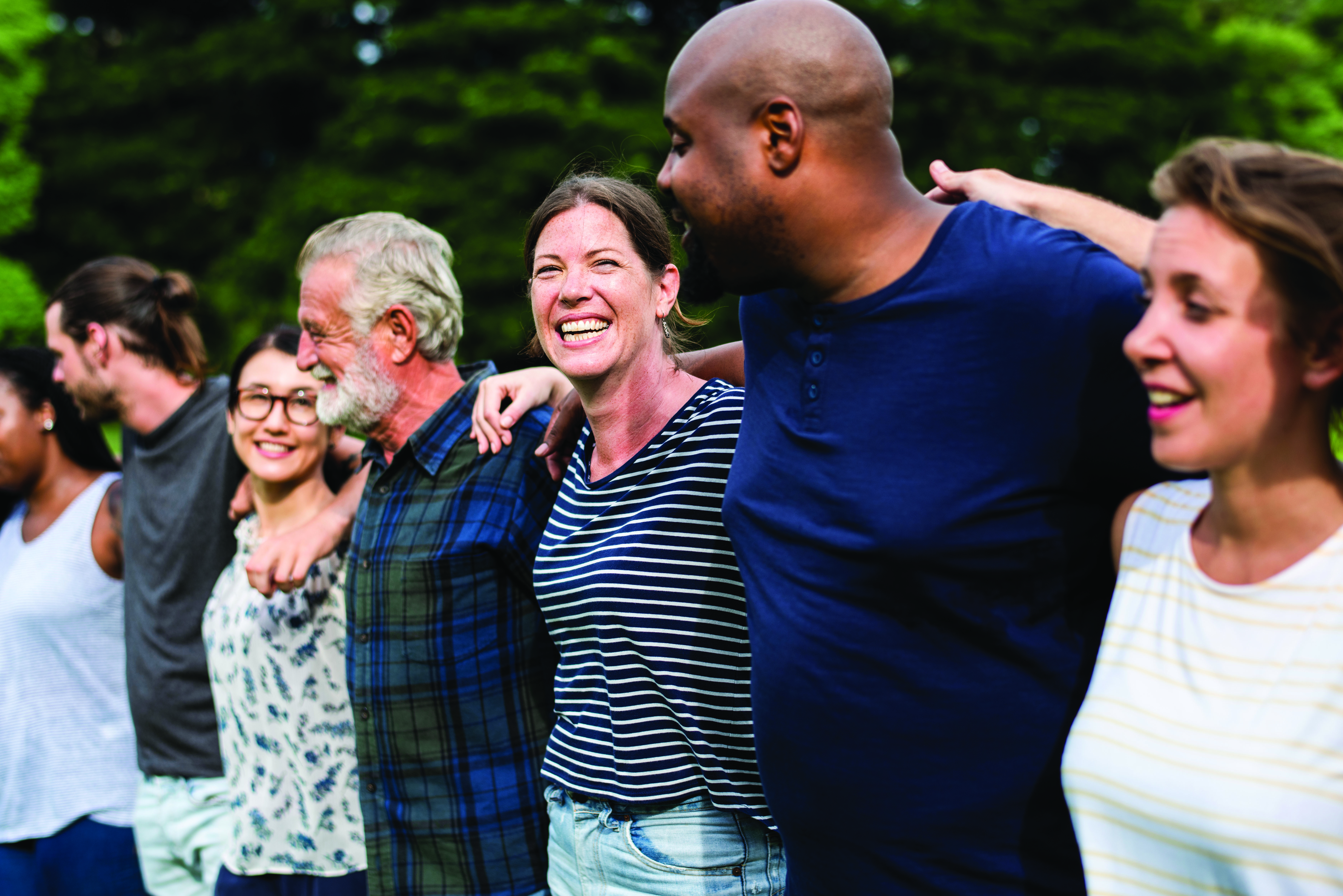 A group of people standing together and smiling with their arms around one another