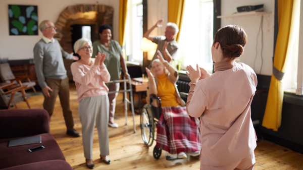 Five residents in a care home listening and moving to music with a group leader 