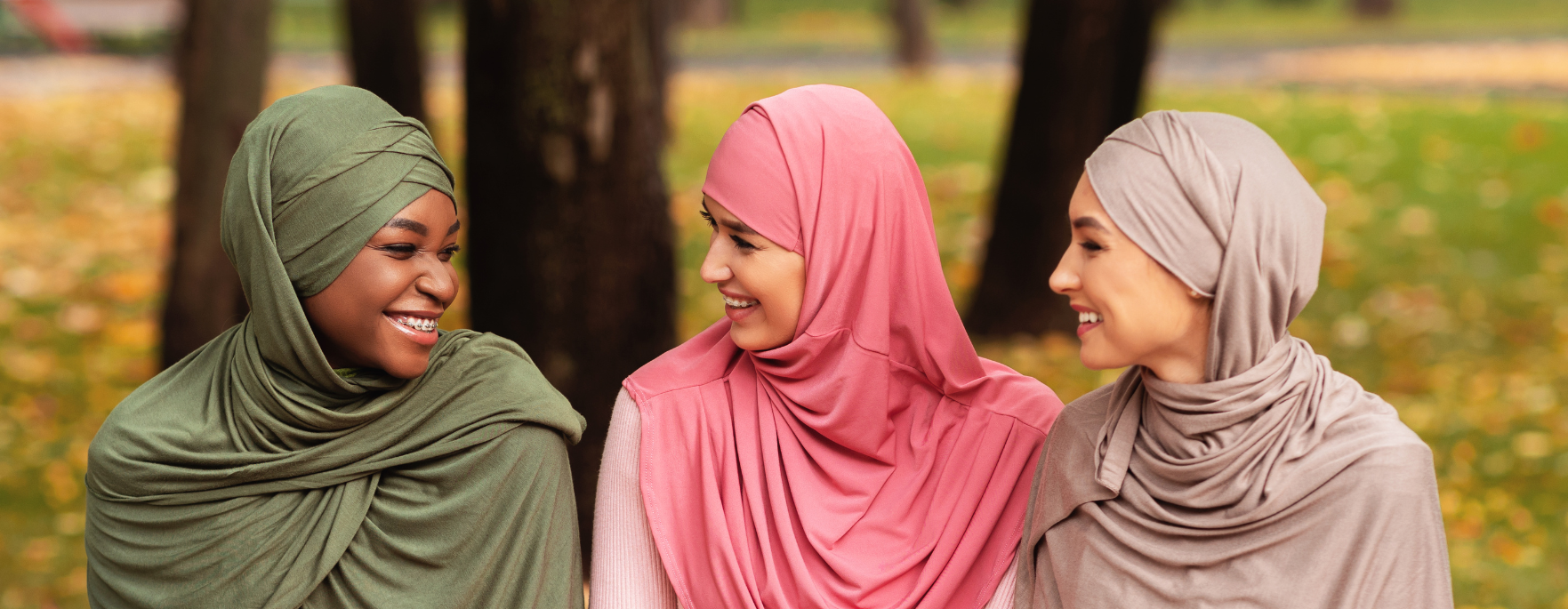 Three women sat outside in a park talking.