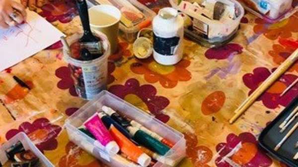 A table with a floral cover holds art supplies