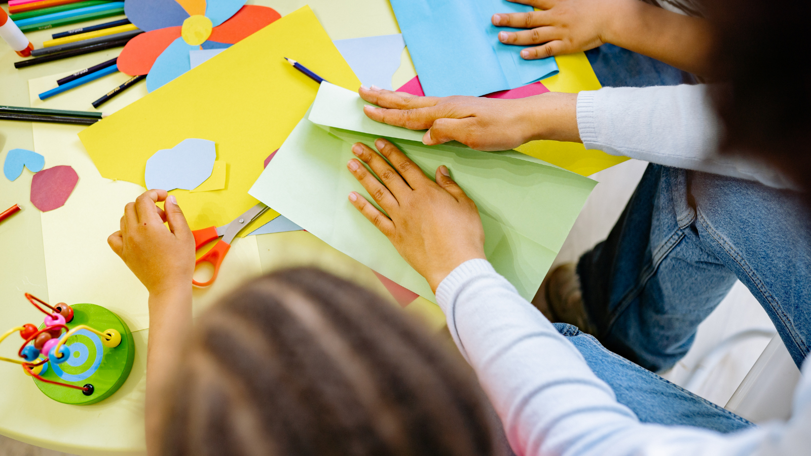 Three ethnically diverse children play with colourful paper crafts