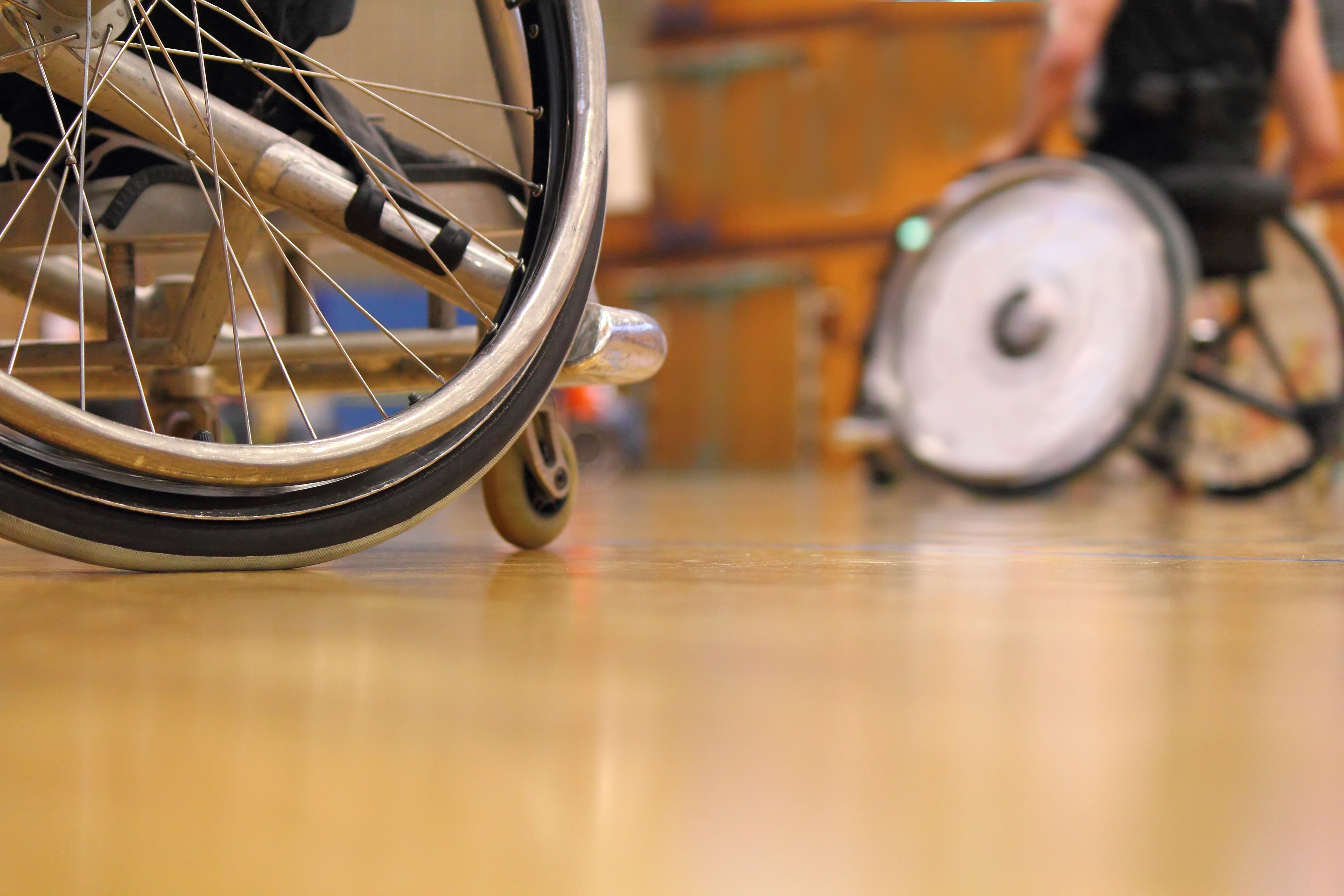 Two wheelchair uses playing basketball in a gym 