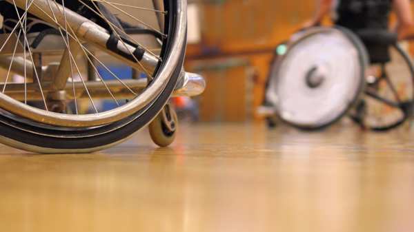 Two wheelchair uses playing basketball in a gym 