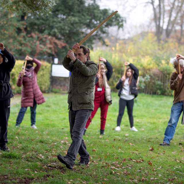A group of people holding sticks take part in the Body Harmony Croydon Community Group in Ashburton Park