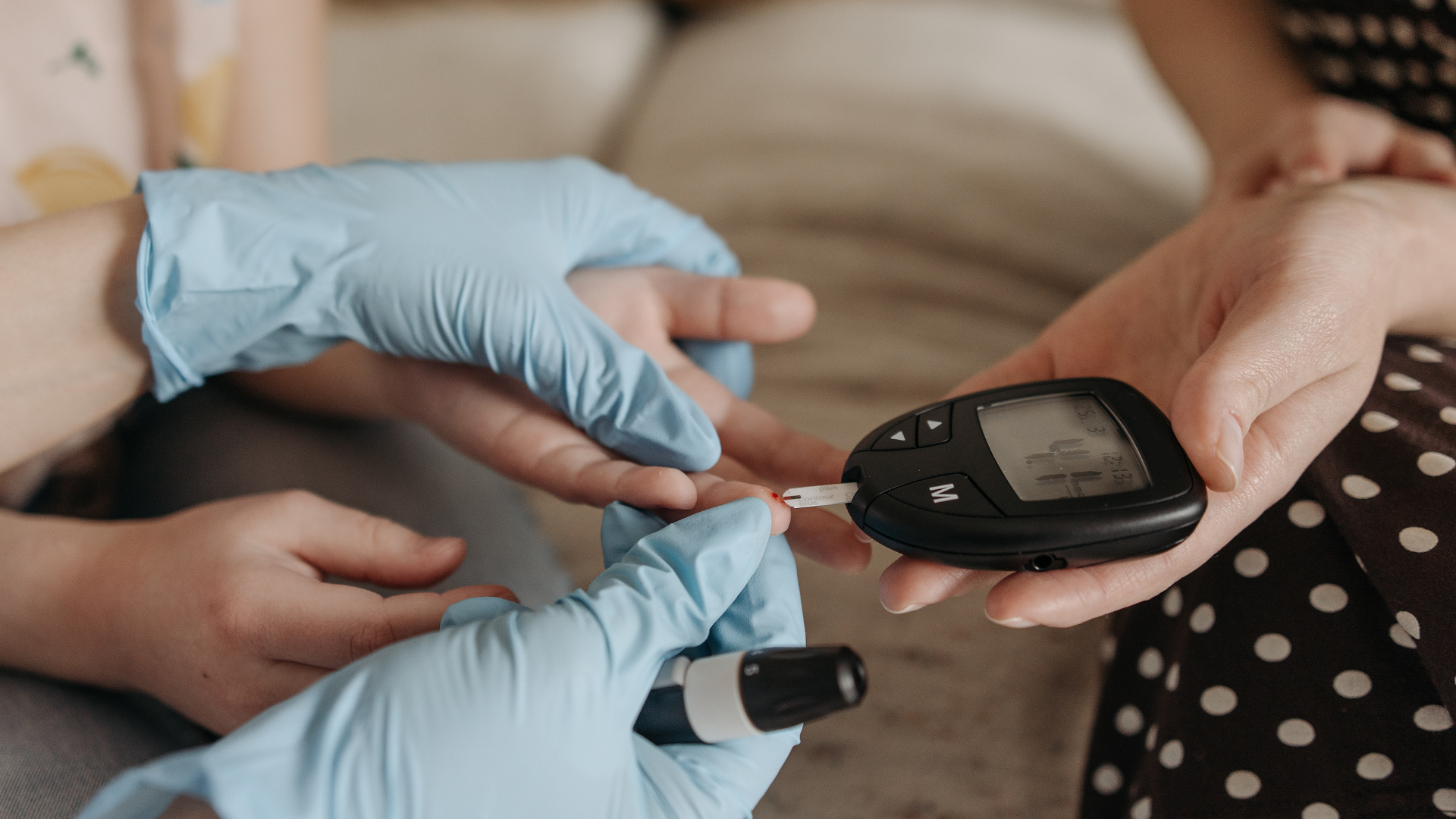 Young person having their blood sugar taken with nurse and carer 