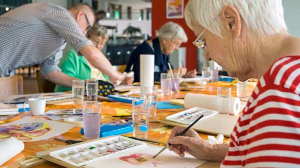 A group of older people painting in an art class 