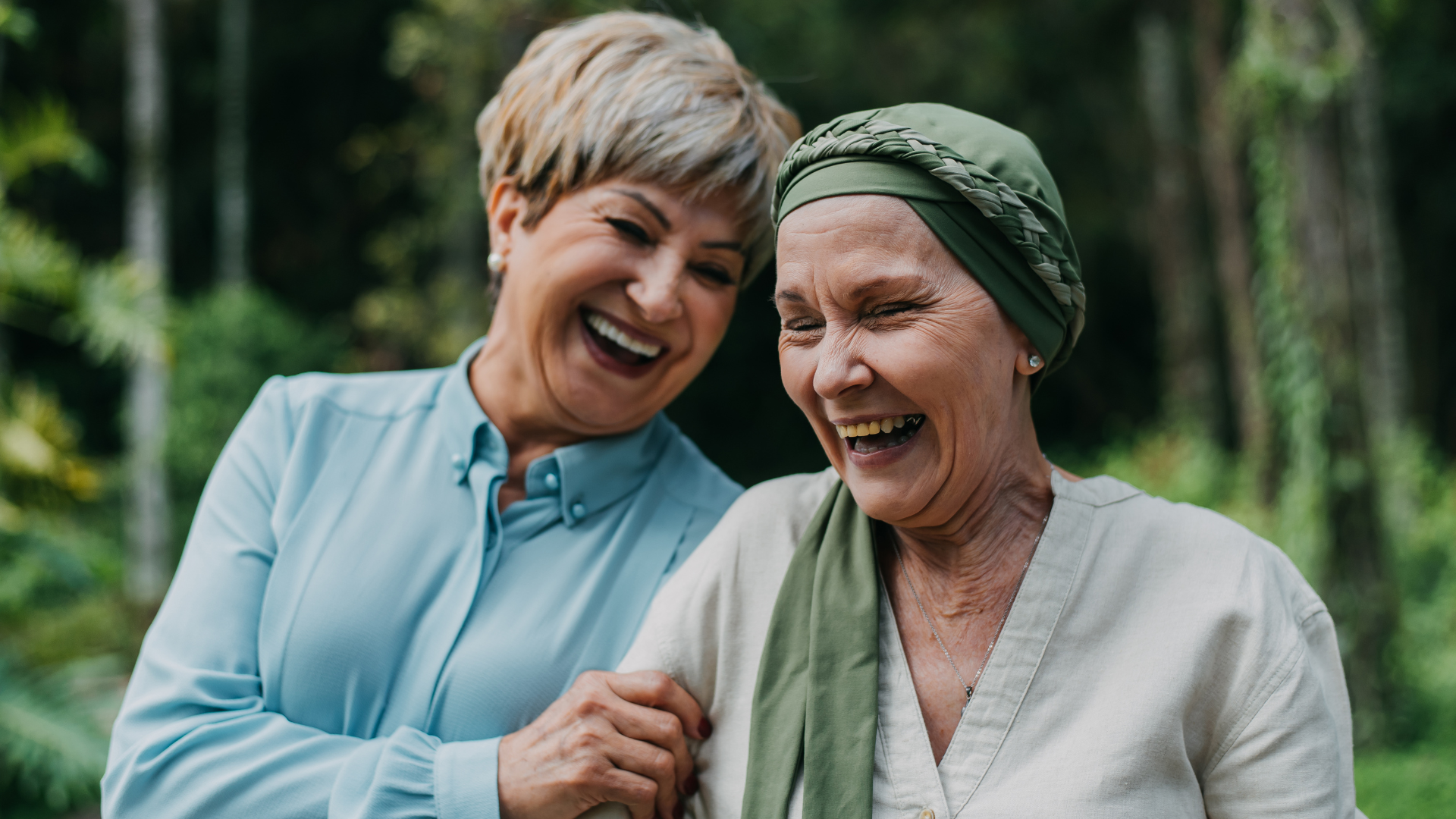 Two older women laugh, one wears a head scarf