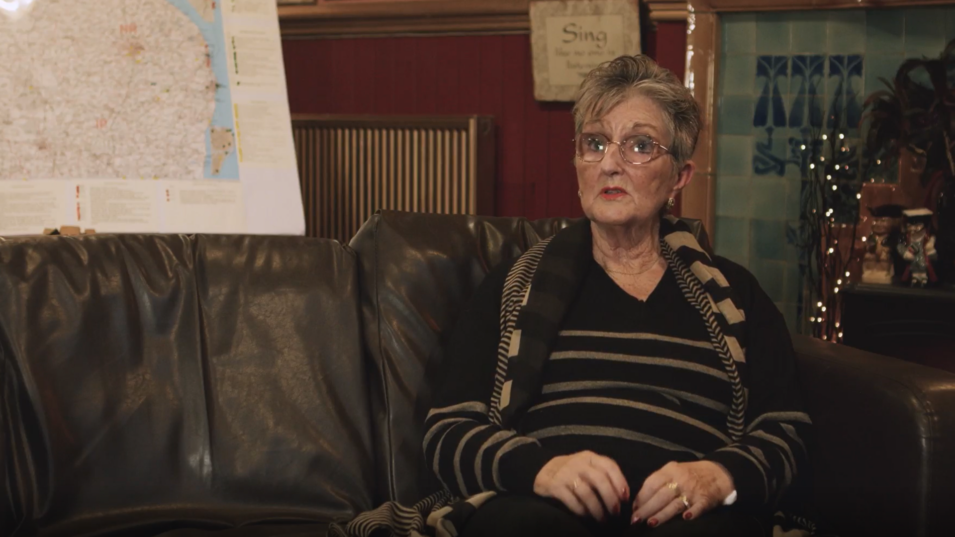 An elderly woman sits on a sofa