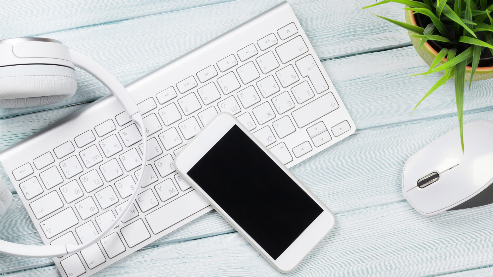 A desk with a phone, headphones, keyboard and mouse