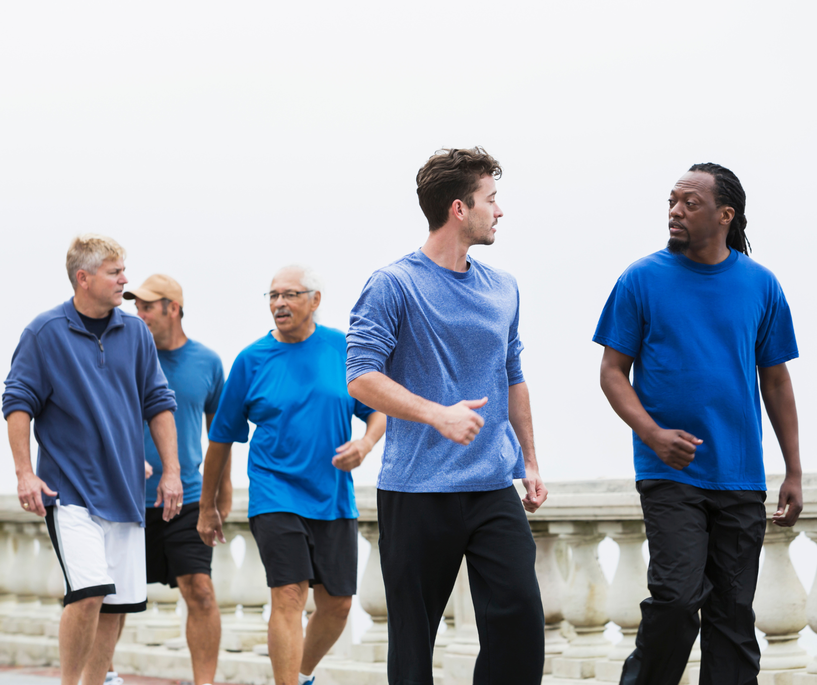 A group of men walking while talking outside.