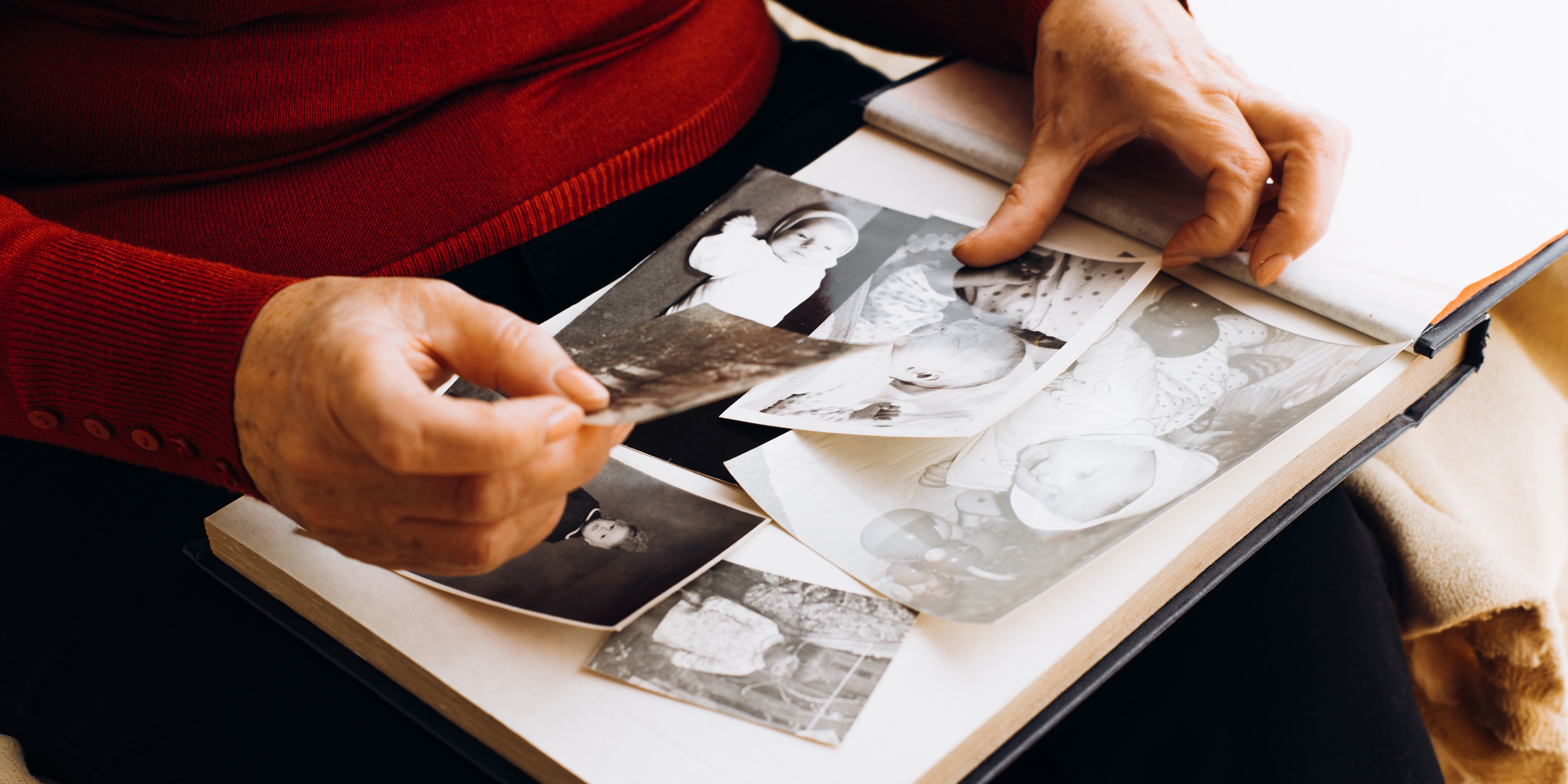 Close up of old photographs in an album and hands carefully holding them