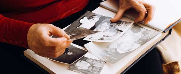 Close up of old photographs in an album and hands carefully holding them