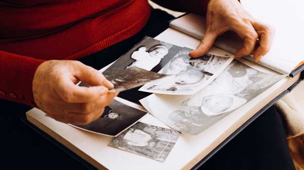 Close up of old photographs in an album and hands carefully holding them