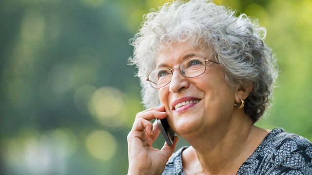 An older woman smiles as she talks on a mobile phone 
