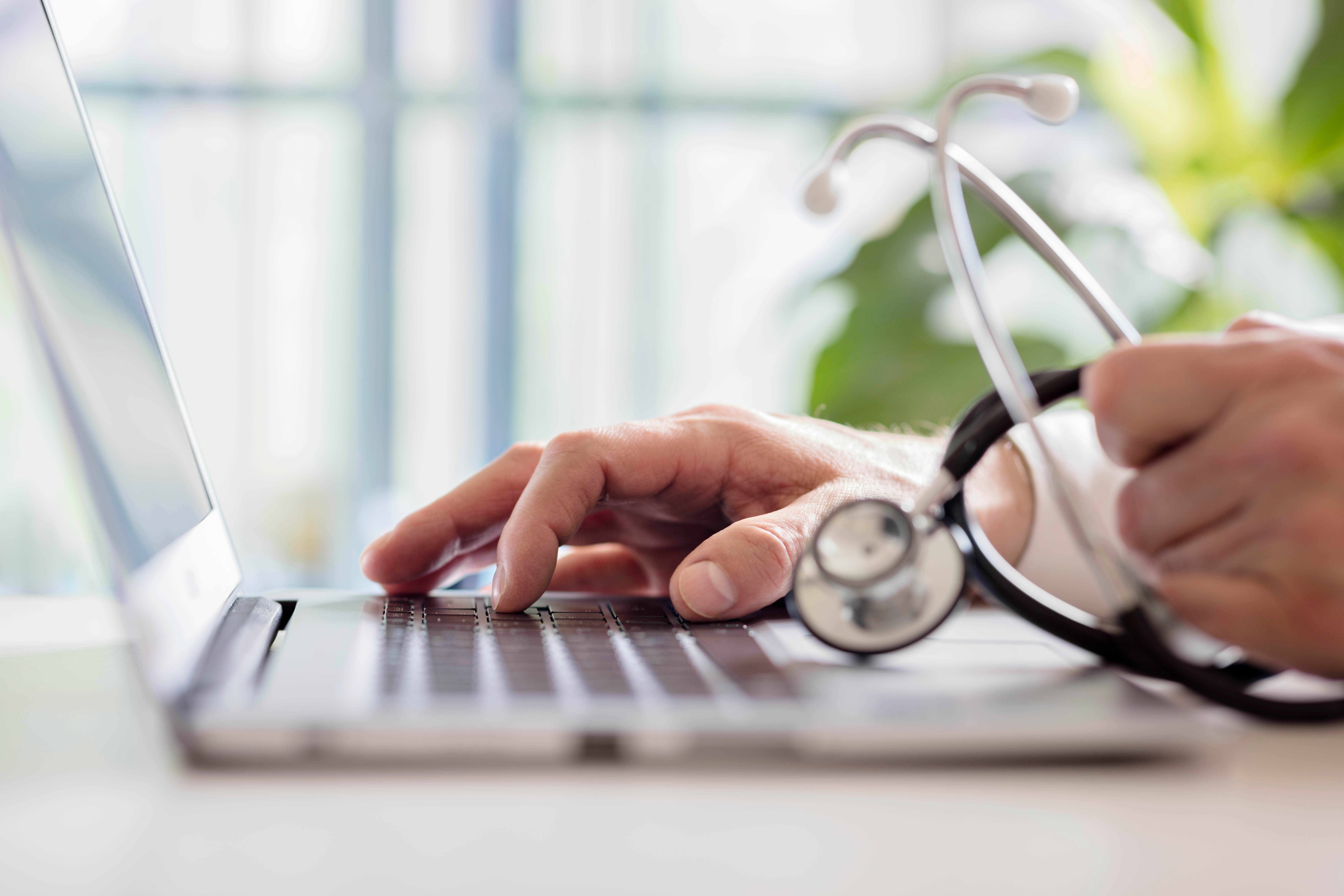 A GP entering patient information into their laptop