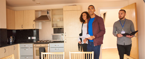 A young couple view a kitchen with an estate agent 