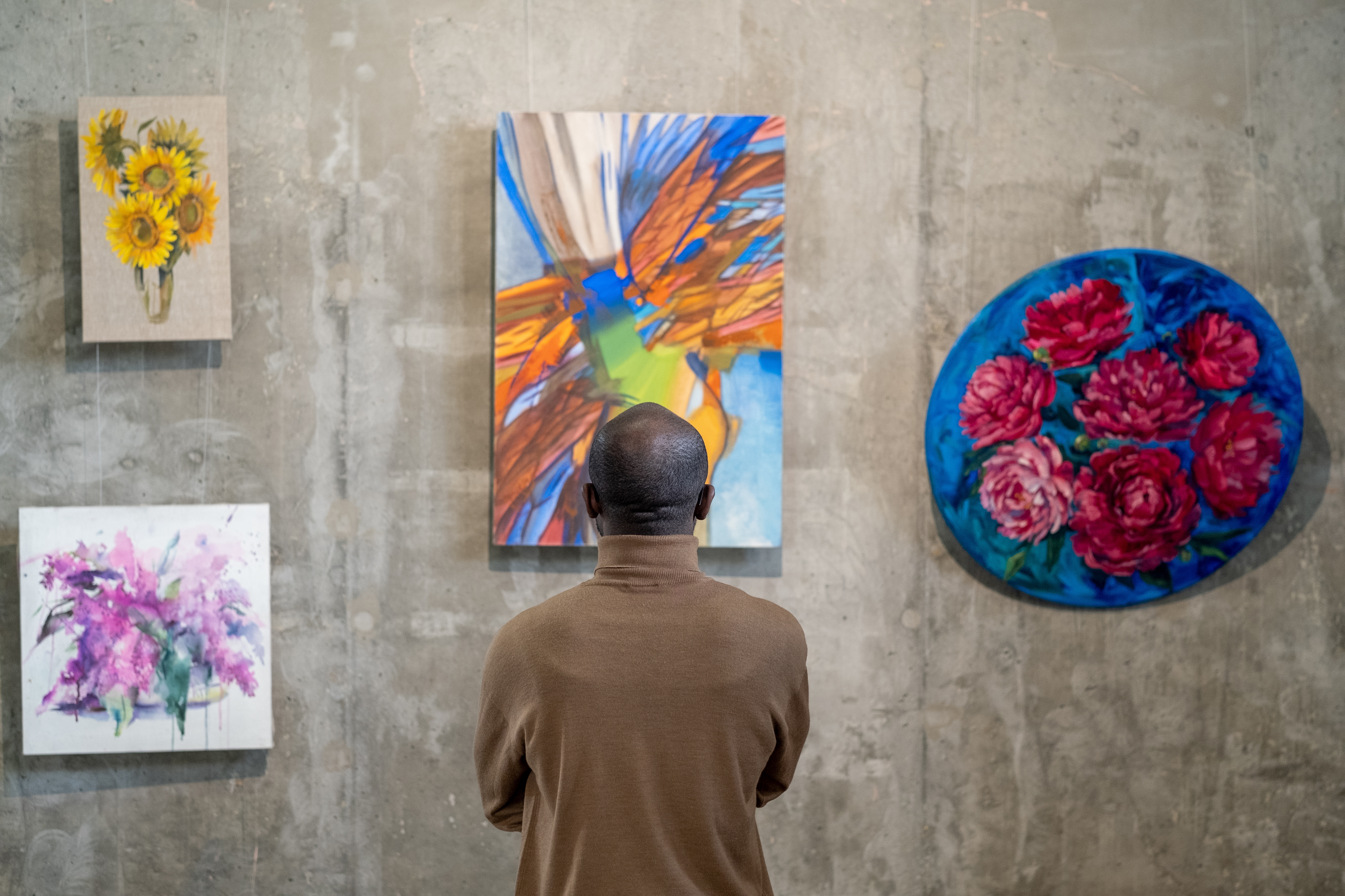 A man looks at paintings at a gallery