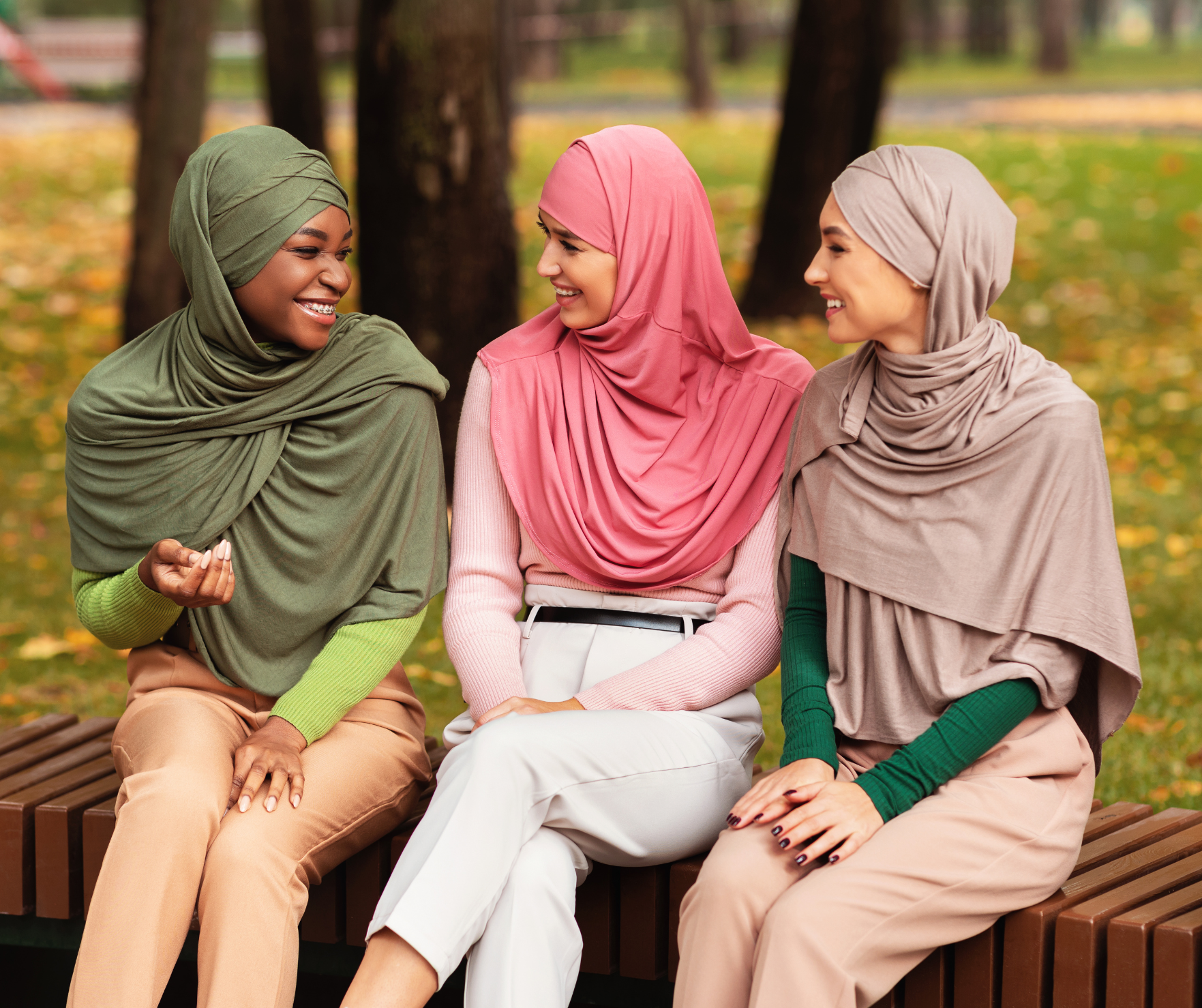 Three women sat outside in a park talking.