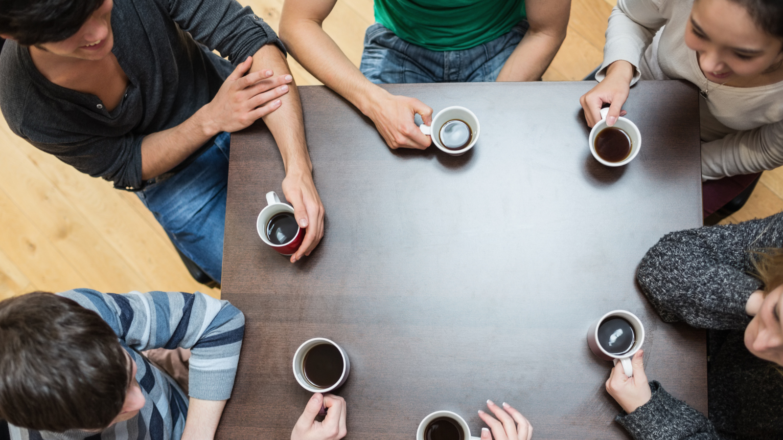 A birds eye view of a group of adults sat around a table drinking coffee