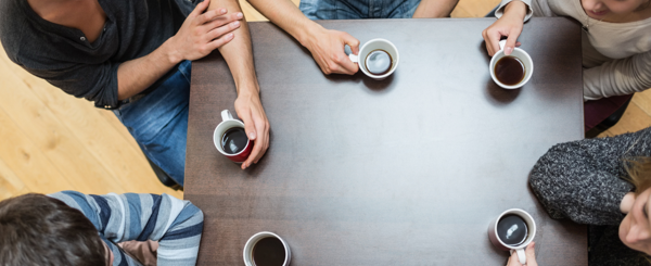 A birds eye view of a group of adults sat around a table drinking coffee