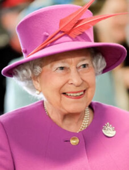 Queen Elizabeth II smiling in a pink coat and hat with orange feathers 