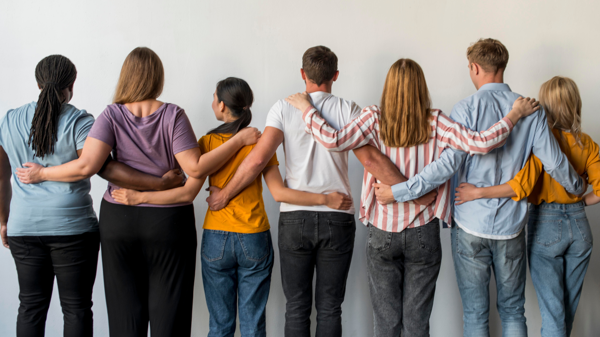 A groups of adults stand in a line with their backs facing the camera. They have their arms around each others back