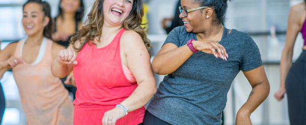 Two women dance together in a group exercise class