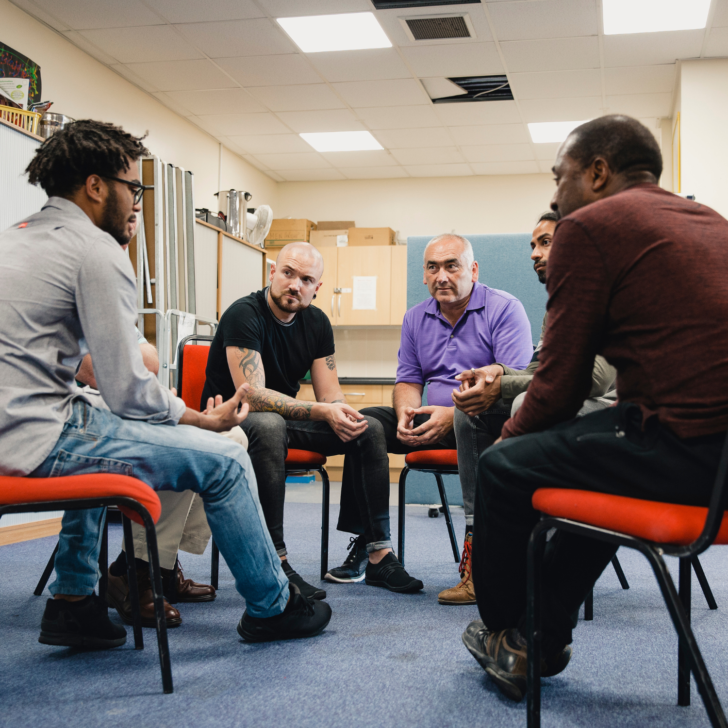 A group of men sat on chairs having a conversation