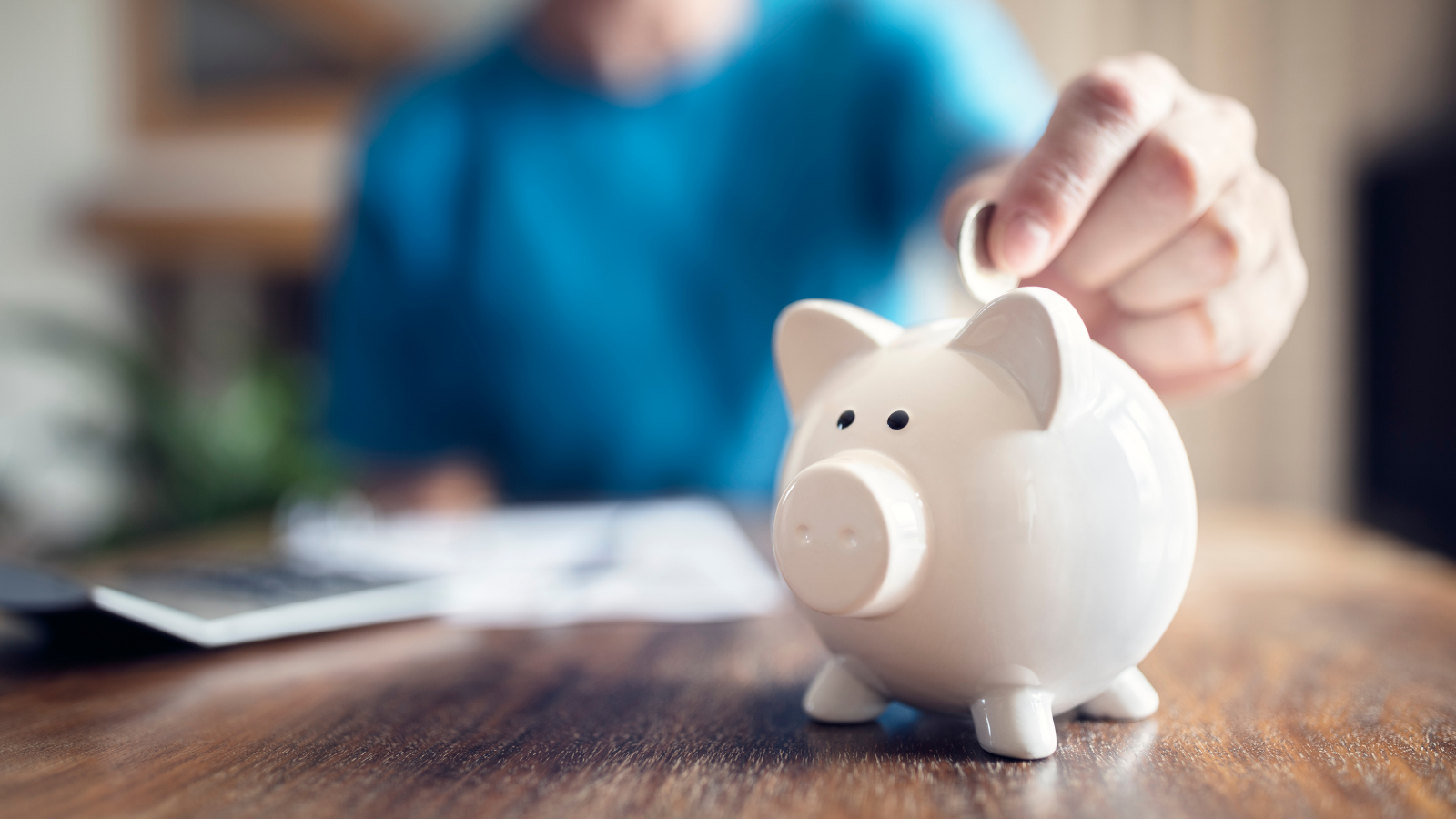 A person drops a coin into a piggybank