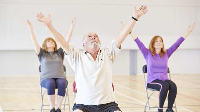 A group of people practicing chair yoga 