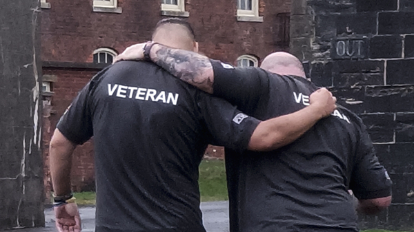 Two veterans hold each other around the shoulders as they walk