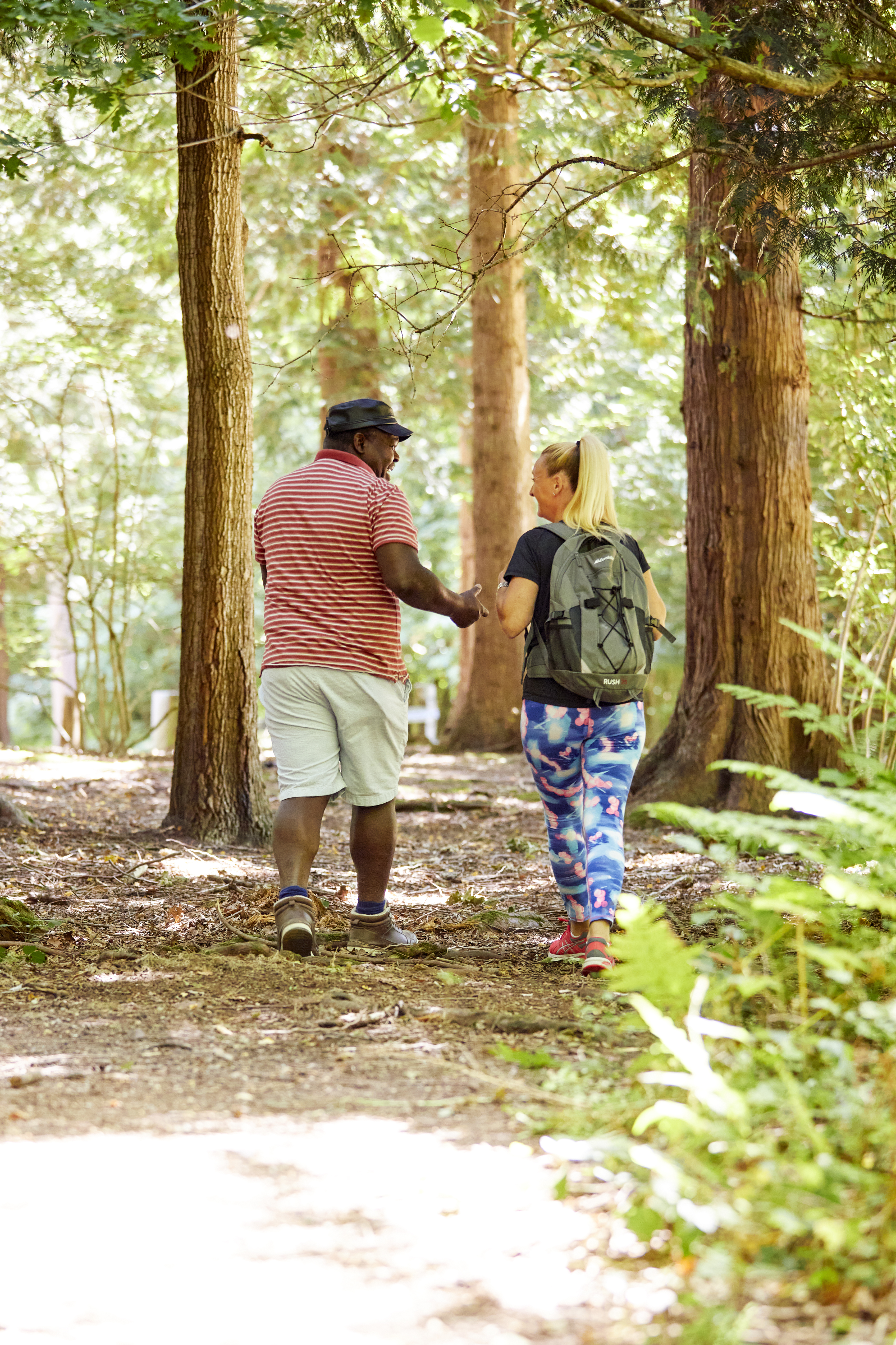 Two people walking in the forest wearing trainers and walking clothes