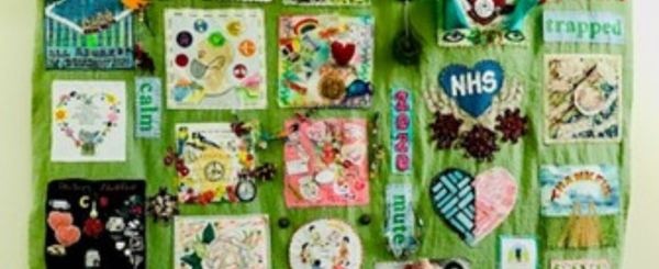 A green blanket is decorated with colourful drawings and paintings