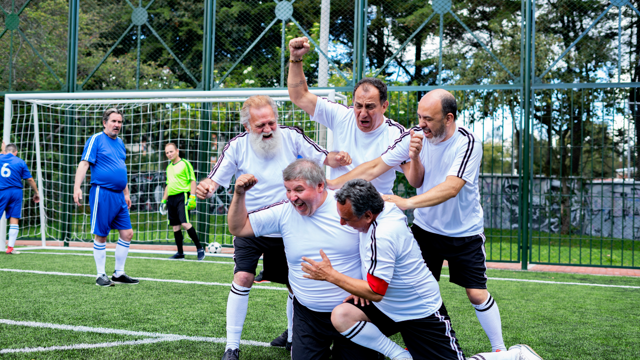 A football team of older mean celebrate a goal